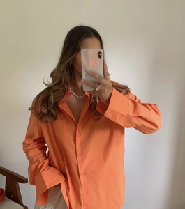 Detailansicht des hellorangen Baumwollhemdes mit Stofftextur und Taschendesign