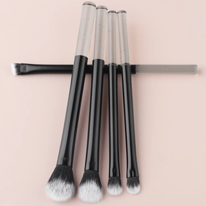 Flat lay of 5-piece makeup brush set with crystal handles on pink background