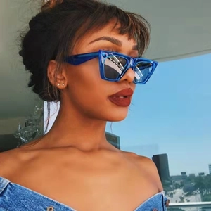 Blaue quadratische Oversize-Sonnenbrille an einem Model vor der Skyline der Stadt