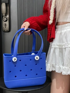 Detail of royal blue EVA beach bag with holes and sturdy handle shown by hand