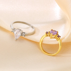 Detailed shot of teardrop zircon rings on elegant gold silk fabric background