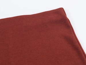 Gros plan détaillé de la texture en maille rouge brique et des coutures de l'ourlet