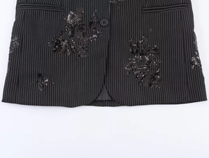 Detail of pinstripe blazer featuring intricate black sequin floral embroidery and pocket