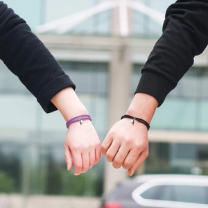 Gros plan des pendentifs cœur magnétiques sur bracelets de couple tressés violets et noirs