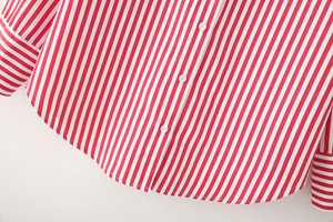 Detail of red and white vertical striped poplin shirt with white buttons and curved hem