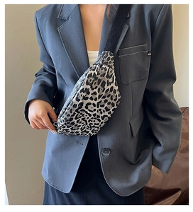 Detail of leopard print crossbody bag with adjustable strap worn over a grey blazer