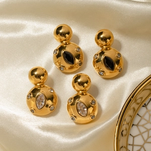 Detailed view of gold ball earrings with black and white stones on golden satin