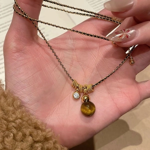 Macro view of gold-plated tiger eye necklace with black beads and zircon pendant