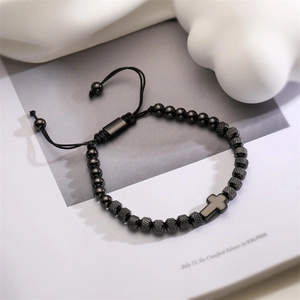 Detail of black beaded adjustable bracelet with cross pendant on an open book