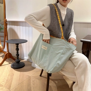 Detail of light blue canvas tote bag with yellow plaid interior and front pocket pouch