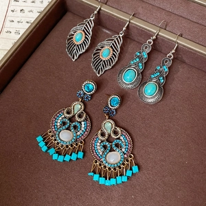 Detail of bohemian leaf earrings with turquoise and tassels on brown leather tray