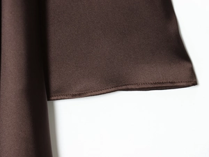 Détail d'une robe en satin marron foncé montrant les coutures et l'éclat du tissu