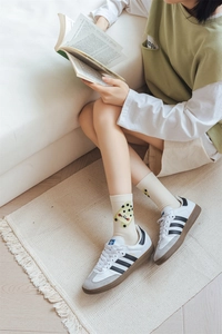 Close-up of off-white socks with yellow cartoon embroidery paired with white sneakers