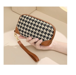 Classic houndstooth clutch bag with brown leather trim and wrist strap held by model