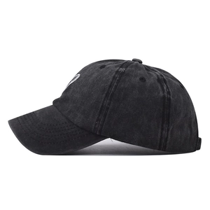 Detail of a washed black cotton baseball cap showing side heart embroidery and stitching