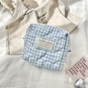 Detail of blue and white plaid quilted cosmetic bag with heart pattern and cloth label
