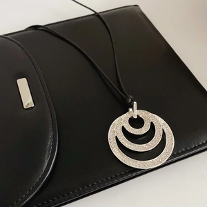 Detail view of silver triple circle pendant with micro-pave crystals on black cord