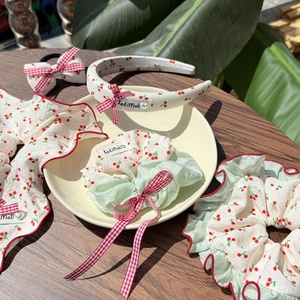 Detail of cherry print hair accessory set with red checkered bow and lace trim