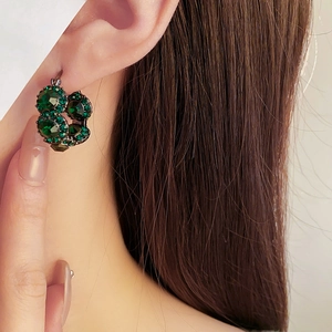 Close-up of French vintage emerald round earrings with sparkling diamond pavé on model