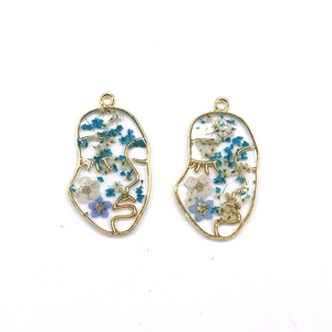 Detail of face silhouette resin pendants with gold frames and real dried flowers