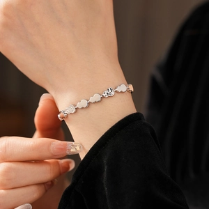 Detailed view of silver pleated heart-shaped links and textured beads on the wrist