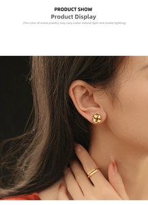 Détail macro d'une boucle d'oreille nœud doré torsadé et d'une bague assortie sur modèle