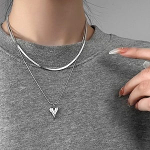 Detail view of double layered silver necklace with flat snake chain and 3D heart pendant