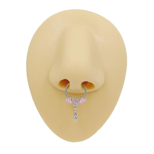 Gros plan d'un anneau de septum argenté avec cœur rose et ailes sur un modèle de nez