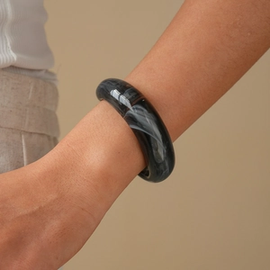 Detailed view of thick acrylic bangle with black and white marble pattern on model wrist