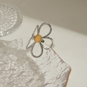 Close-up of bicolor hollow flower ring with silver petals and golden center on glass