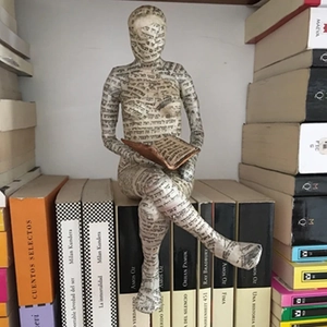 Close-up of reading woman figurine with Hebrew text pattern on bookshelf decor
