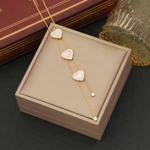 Gold stainless steel necklace featuring three heart pendants with pavé crystals and white inlay
