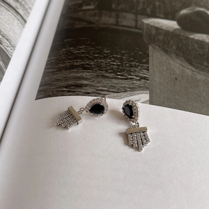 Detail of 925 silver earrings with black pear-shaped stone and tassel diamonds