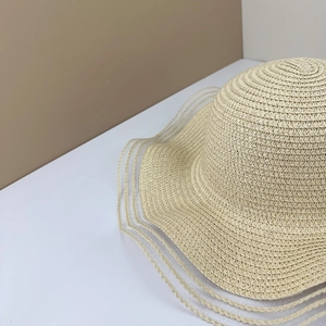 Detail of woven straw sun hat showing wide brim with sheer mesh decorative stripes
