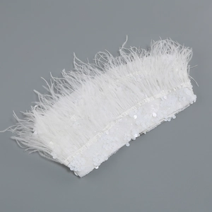 Detail of white ostrich feathers and sequin embellishments on women's luxury outfit fabric