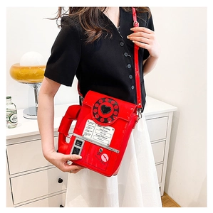 Detail of red retro phone shaped crossbody bag featuring a dial and glossy finish