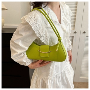 Close-up of green shoulder bag featuring a golden crescent buckle and knotted strap details