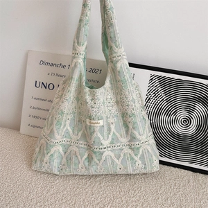 Detailed close-up of mint green lace embroidery and the brand tag on a tote bag