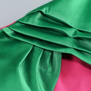 Close-up of pink and green satin fabric showing elegant pleated details and smooth texture