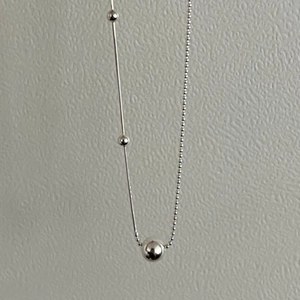 Macro detail of 925 sterling silver ball chain necklace with minimalist metal bar pendant
