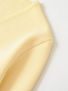 Gros plan sur les mailles fines et les coutures d'épaule du pull jaune clair