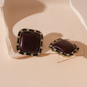 Close-up of vintage square stud earrings with burgundy stones and rhinestone inlay