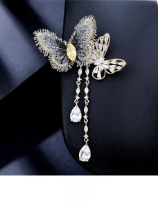 Vue macro d'une broche papillon avec broderie et pompons en zircon sur fond noir