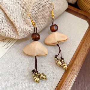 Tiger eye wooden bead earrings with a vintage golden acorn pendant on burlap background