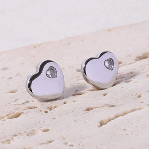 Detailed close-up of 12mm 18K gold plated heart earrings with sparkling zircon on stone surface