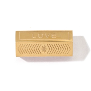 Détail d'un pendentif rectangulaire doré avec gravure LOVE et rayons géométriques élégants
