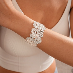 Close-up of wide silver cutout bangle with intricate floral filigree patterns on wrist