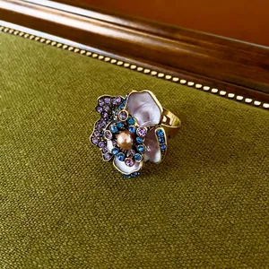 Vintage floral ring with champagne pearl and purple crystals on green textured fabric