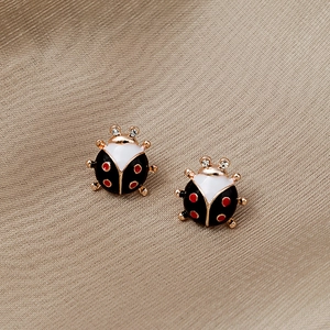 Détail macro de boucles d'oreilles coccinelle avec émail rouge et noir et zircons brillants