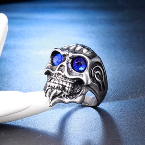 Detailed close-up of a vintage silver skull ring with deep blue crystal eyes